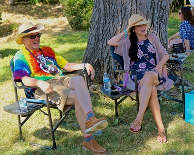 People relaxing outdoors at a Lodi Winegrape Commission event, enjoying wine and conversation under a large tree.