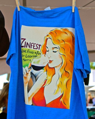 Blue T-shirt with Lodi Winegrape Commission artwork featuring a woman enjoying wine.