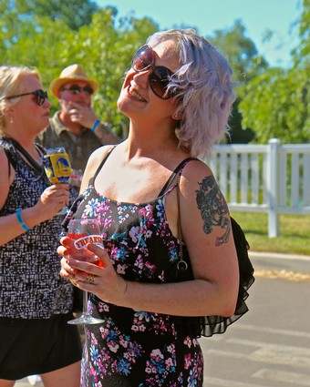 Woman with purple hair and sunglasses enjoying wine at Lodi Winegrape Commission event.