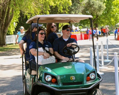 Group of people enjoying a golf cart ride at a Lodi wine event in a park setting.