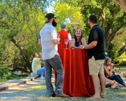 People enjoying a wine tasting event outdoors with trees and sunlight in Lodi, California.