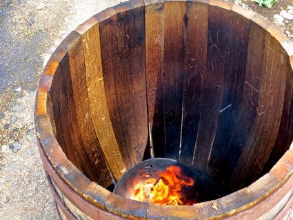 Wooden wine barrel with fire inside, used for wine aging in Lodi, California.