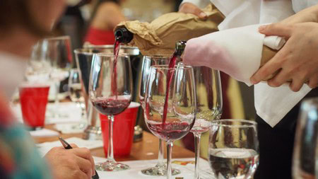 Wine being poured into glasses at a wine tasting event, showcasing Lodi winegrapes.