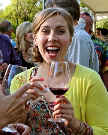 Happy woman holding a glass of red wine at a wine tasting event in Lodi, California.