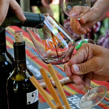 People enjoying wine tasting at Lodi Winegrape Commission event with wine glasses and bottles.