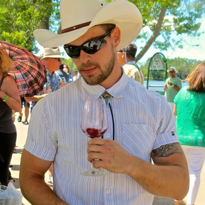 Man with cowboy hat and sunglasses enjoying wine at Lodi Winegrape Commission event.