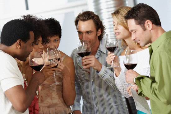 Group of diverse people enjoying wine tasting, holding glasses of red wine, at a wine event.
