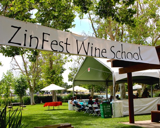 ZinFest Wine School banner at outdoor event in Lodi, California with tents and attendees.
