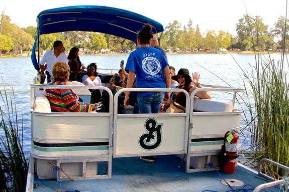 Group of people enjoying a boat tour on a lake, with staff guiding the tour and scenic nature in the background.