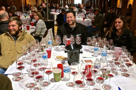 People enjoying wine tasting at a Lodi Winegrape Commission event with multiple wine glasses and bottles on the table.