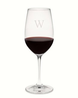 Elegant wine glass filled with red wine, featuring a subtle 'W' monogram, on a plain white background.