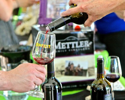 Person pouring red wine into a glass at a wine tasting event, showcasing Lodi wine culture.