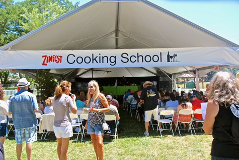 People attending a cooking school event under a tent with Lodi Winegrape Commission branding.