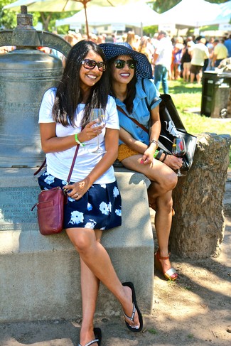 Two women enjoying wine at the Lodi Winegrape Festival outdoors with a crowd in the background.