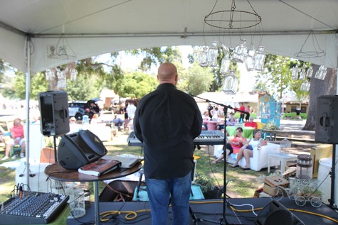 Musician performing at Lodi Winegrape Commission event with audience in park setting.