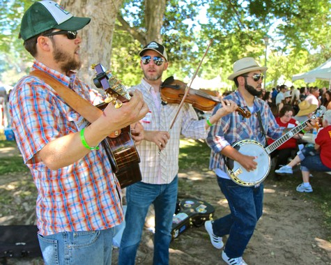 Musicians playing string instruments outdoors at a Lodi wine event with audience in background.