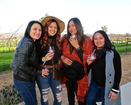 Group of four women enjoying wine tasting outdoors at Lodi Winegrape Commission event.