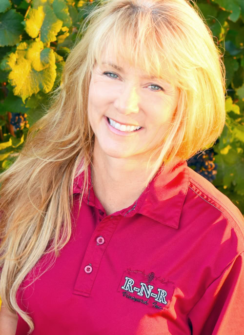 Smiling woman in a red polo shirt with Lodi Winegrape Commission logo outdoors.