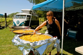 Woman serving large pan of food at Lodi Winegrape Commission outdoor event.