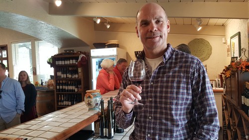 Man enjoying wine tasting at Lodi Winegrape Commission event in a cozy winery setting.